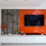 TV media wall in matching grey gloss and wood effect laminate. Paired with a bold orange glass panel to match the pops of colour throughout the design.