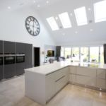 A mixture of light grey gloss and matt graphite handless Hacker kitchen units with matching stianless steel handless trim and plinth with feature micro dot plinth lights.