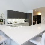 Glamours Niel white shimmer quartz worktop adorning a highend Miele induction hob and discrete matching down draft extractor hood.