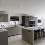 Light bright and earthy warm tones throughout this Hacker handless kitchen help create a welcoming atmosphere with the cool modern look of the appliances and fixtures.
